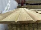 Close-up of light-brown wooden planks stacked outdoors in a lumber yard.